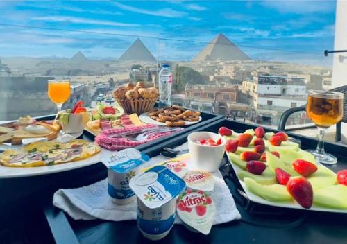 GizaMuseum comfort view Giza ' pyramids的一张桌子,上面摆放着食物和饮料,享有金字塔的景色