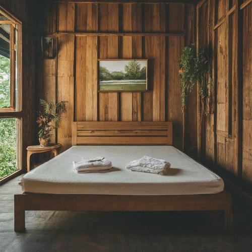 Ban Bung Rua Yaiบ้านเจ้าสัวน้อย的木制房间的一个床位,上面有两条毛巾