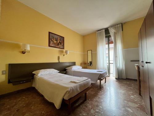 切萨诺博斯科内Hotel Parini的黄色墙壁客房的两张床