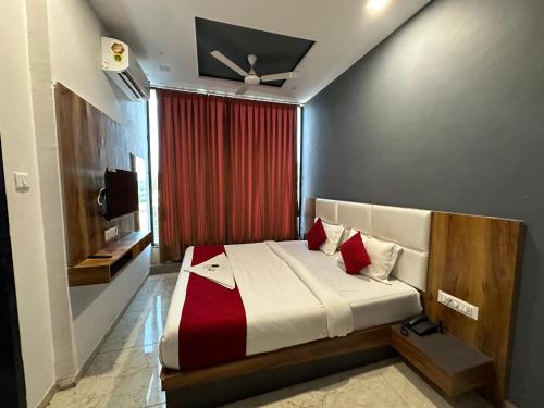 苏拉特Hotel Dumas Near Airport的一间卧室配有一张带红色窗帘的床