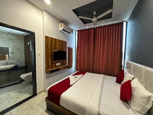 苏拉特Hotel Dumas Near Airport的一间卧室配有一张床,浴室配有电视。