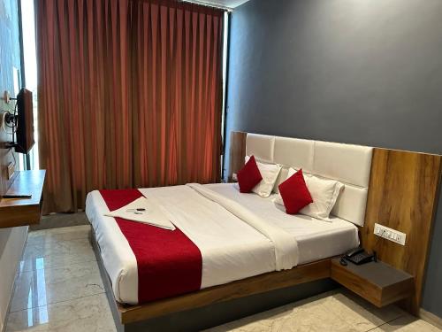 苏拉特Hotel Dumas Near Airport的一间卧室配有一张带红色和白色枕头的大床