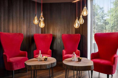 林茨Amedia Linz, Trademark Collection by Wyndham的一间设有红色椅子和桌子及灯的房间