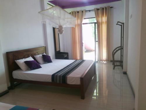 锡吉里亚Tezara Home Stay的一间卧室配有一张带紫色枕头的床