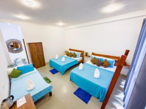 达瓦拉维Lily Resort Udawalawe的配有蓝色床单的客房内的两张床