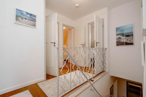 提努姆Ferienhaus Sprotte的一条带白色墙壁的走廊和一个带玻璃门的楼梯