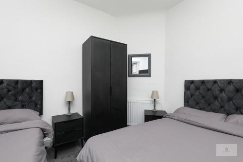 CrankLovely 2-Bedroom Bungalow Sleeps 6 with Garden and Off Road Parking by Amazing Spaces Relocations Ltd的一间卧室设有两张床和黑色橱柜