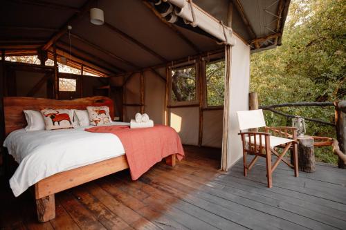 ChungaKasabushi Camp的一间卧室,在木甲板上配有一张床