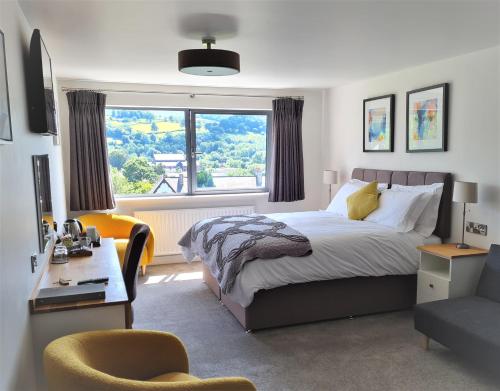 布雷肯Camden Lodge B&B and Cottage Brecon的一间卧室配有一张床、一张书桌和一个窗户。