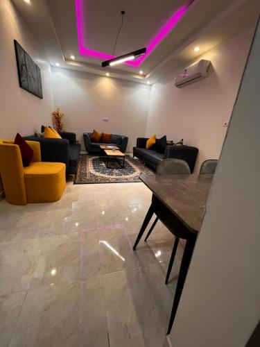 Al Fayşalīyahشقق الروشن الجوفي的带沙发、桌子和紫色灯的客厅