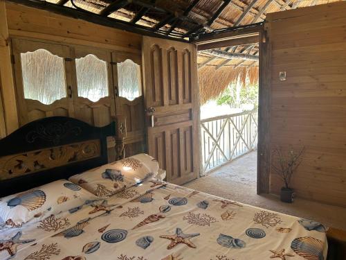 卡塔赫纳Punta Arena EcoHostal and EcoFit – Your Eco-Friendly Oasis 02的一间卧室设有一张床,门通往门廊