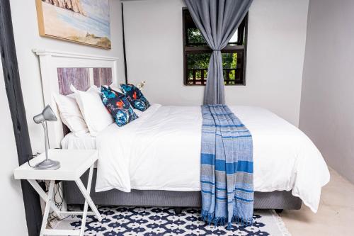 波罗瓜尼Seloko Guest Cottage的一间卧室配有一张床、一张桌子和一个窗户。