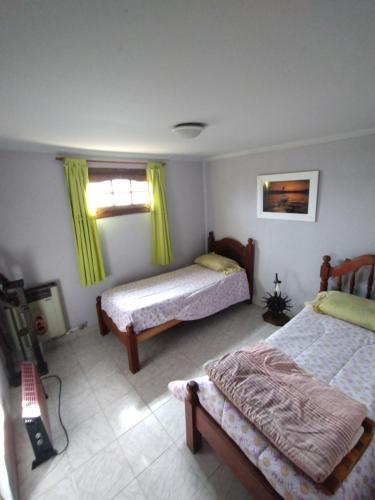 乌斯怀亚Ushuaia hospedaje的一间卧室设有两张床,窗户配有黄色窗帘