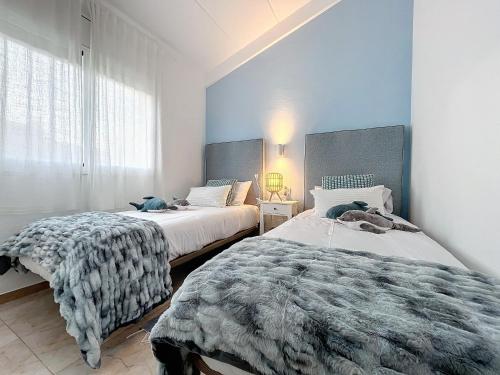 埃斯塔蒂特Mar Blau Estartit Rental的卧室设有两张床铺和蓝色的墙壁