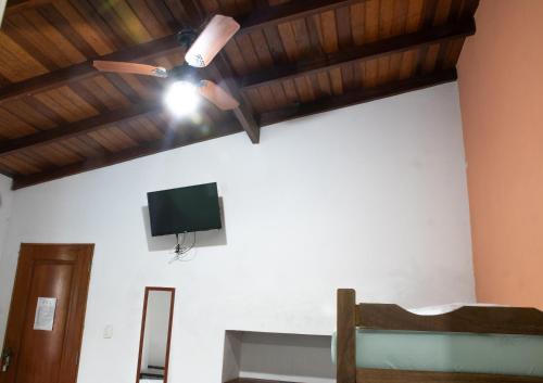 卡拉瓜塔图巴Recanto da Rose Guesthouse的客房设有吊扇和墙上的电视。