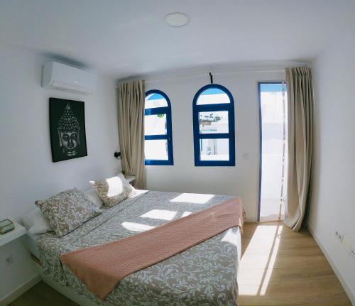 马斯帕洛马斯Bungalow Terrace&Pool near the Beach的一间卧室设有一张床和两个窗户。