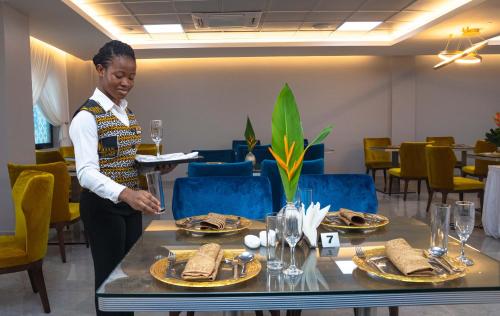 阿克拉机场东橡树广场酒店的站在桌子旁的女人,在桌子上摆着食物
