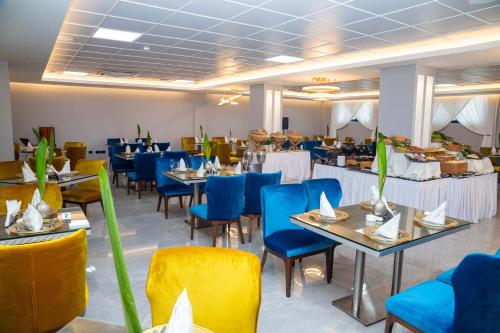 阿克拉机场东橡树广场酒店的一间配备有桌子和蓝色椅子的用餐室