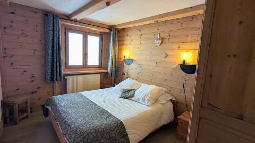 拉赫兹耶尔Chalet Lè Lodzé - Pieds des pistes的木制客房内的一间卧室,配有一张床