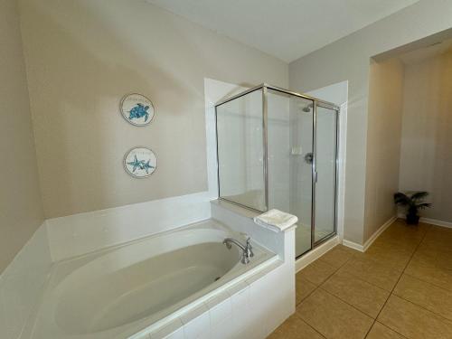奥兰多Vista Cay Getaway Luxury Condo by Universal Orlando Rental的带浴缸和玻璃淋浴间的浴室。