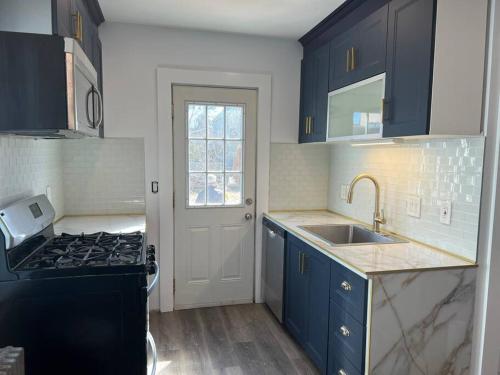 沃特敦Charming 3BR, 1BA Near Heart of Boston!的厨房配有蓝色橱柜、水槽和炉灶。