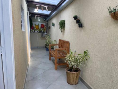 瓜鲁柳斯Hostel Quartos com banheiro individual perto do Aeroporto的走廊上设有长凳和盆栽植物