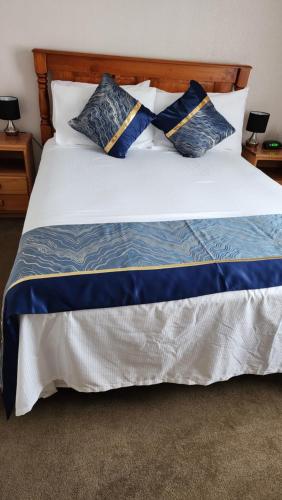 奥克兰Bed & Breakfast @ Unsworth Heights Albany的一张配有蓝色和白色枕头的大床