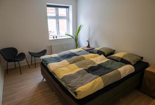 斯文堡Hyggelig byhus i stueplan med solrig gårdhave的一间卧室配有一张带两把椅子的床和一扇窗户