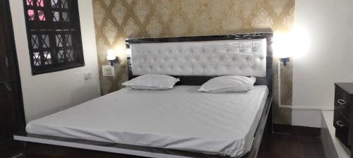 那格浦尔Raen Basera Home Stay的卧室内的一张带白色床单和枕头的床
