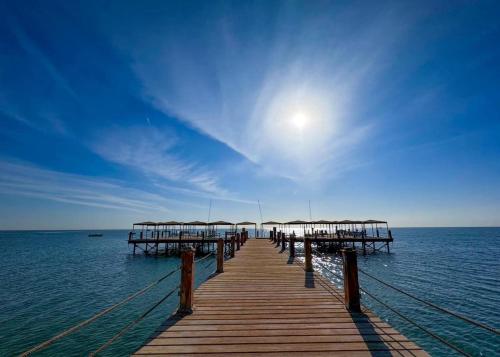 艾因苏赫纳5-BR beachfront Villa on Red Sea - stunning view的水面上带遮阳伞的木码头