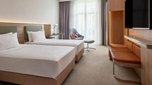 什未林Courtyard by Marriott Schwerin的酒店客房设有两张床和电视。