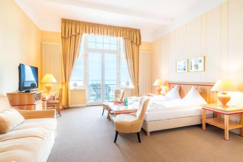 赛巴特班森Strandhotel Möwe的酒店客房配有床、沙发和电视。