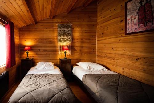 AlzonneL'Escale Occitane的小木屋内的两张床,配有两盏灯