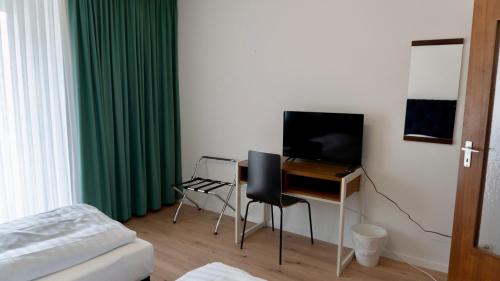 勒沃库森Haven - Hotel Am Stadion的一间卧室配有一张桌子、一台电视和一张床