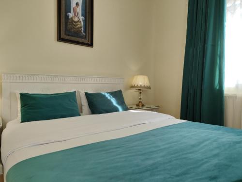 库塔伊西Crown Hotel的一张铺有蓝色和白色床单的床和窗户
