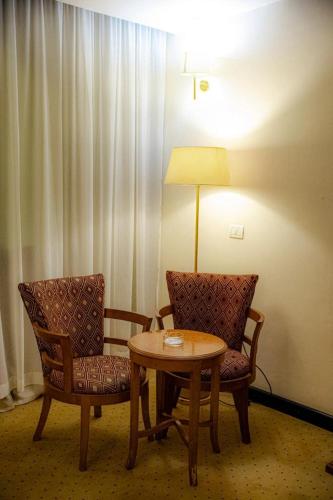 开罗paradise hotel的一间设有两把椅子、一张桌子和一盏灯的房间