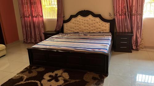 弗里敦Berakah cozy Rentals的卧室内的一张大床,配有窗帘和地毯