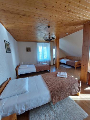 SmalininkaiAšmonienės svečių namai "Senoji mokyklėlė"的一间卧室设有两张床和木制天花板