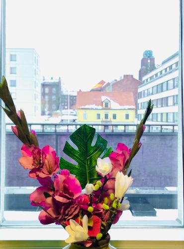 拉赫蒂Kaunis kattohuoneisto Lahden keskustassa的花瓶装满鲜花,坐在窗户里