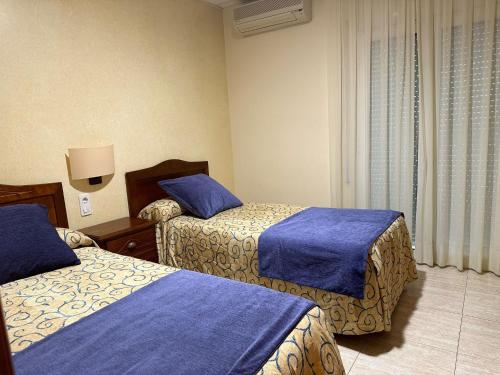 霍斯皮塔勒·德尔英福桑丘酒店的酒店客房,配有两张带蓝色床单的床