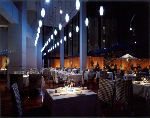 川崎莫利诺新百合丘酒店的餐厅配有白色的桌椅和灯光