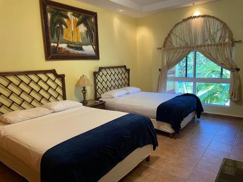 特拉Honduras Shores Plantations的一间卧室设有两张床和窗户。