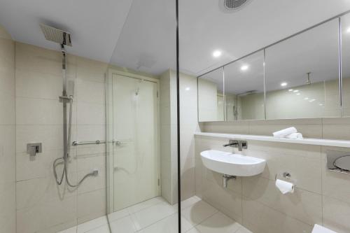 达尔文Oaks Darwin Elan Hotel的带淋浴、盥洗盆和镜子的浴室