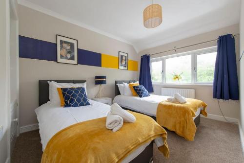 查塔姆The Shield的配有两张蓝色和黄色窗帘的床铺