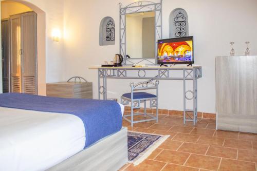 马萨阿拉姆Protels Beach Club & SPA的一间卧室配有一张床和一张桌子及一台电视