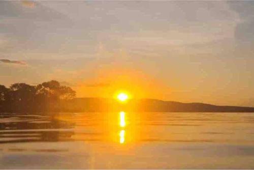 圣若昂-达巴拉Casa de temporada no Lago de Furnas-acesso a represa的日落在水体上,日落在太阳下