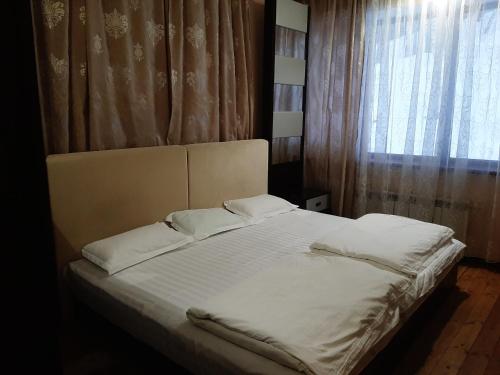 BesqaynarГостевой дом Almatau House的一张带白色床单和枕头的床,靠窗