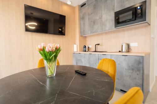 里沃Apartament z Tarasem Morska 6 Rewal 50m do morza的一张带黄色椅子的黑色桌子和花瓶