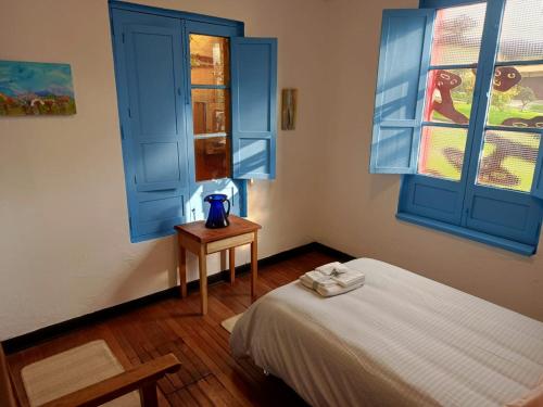 波哥大Casa-Arbol的一间卧室设有蓝色窗户、一张床和一张桌子