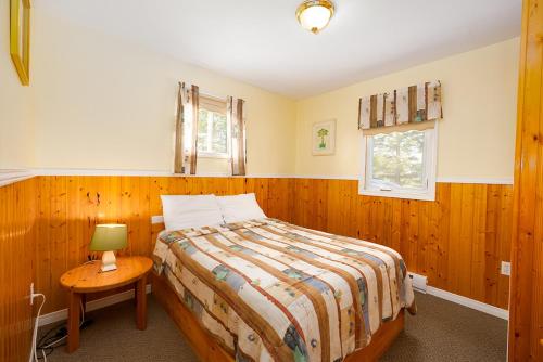 布拉克利海滩Fiddler's Green Country Cottages的一间卧室配有一张床和一张带台灯的桌子